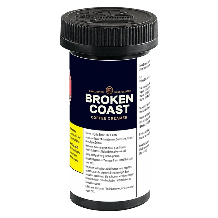 Three-quarter view of the Broken Coast Coffee Creamer black plastic jar with navy label, visible nutrition text and ribbed screw cap.