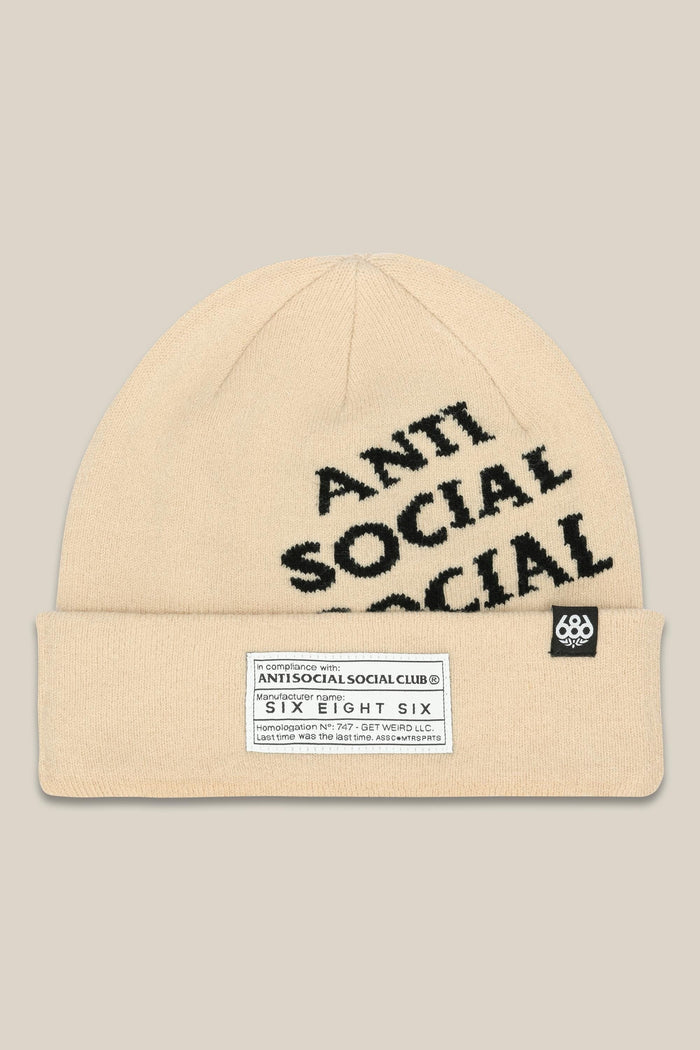 The 686 ASSC Club Beanie by 686 is a beige acrylic knit mens beanie with ANTI SOCIAL SOCIAL in bold black letters, a white rectangular label on the cuff, and a small side tag featuring a white logo.