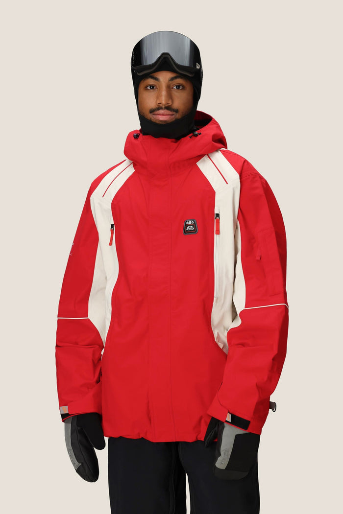 A person wearing the 686 Men's 2002 X3 3L Shell Jacket, black gloves, a black helmet, and ski goggles stands against a plain light background.