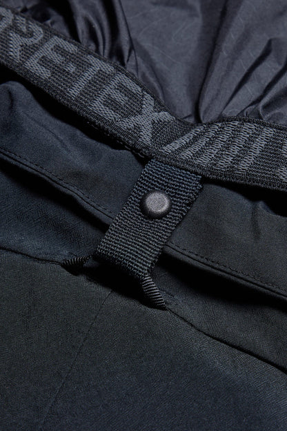 Close-up of the 686 Men's Deconstructed™ Denim Pant in black, showing its waterproof insulated design with a snap button waistband and visible "GORE-TEX" branding, emphasizing the textured fabric and precise construction by 686.