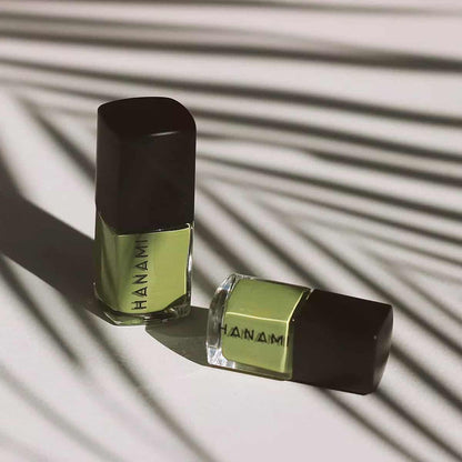 Two bottles of Hanam nail polish on a textured surface with shadows.