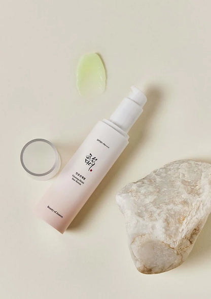 Skincare bottle with a rock and green leaf on a beige background