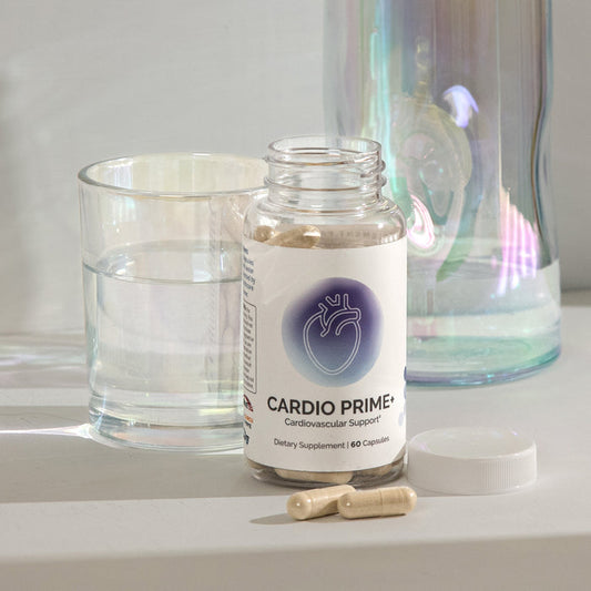 InfiniWell Cardio Prime cardiovascular support supplement bottle with open lid, capsules, and glass of water.