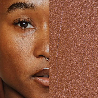Model next to swatch of Elate Beauty Creme Concealer in the shade 'CW6', for medium deep warm skin tones. A two-in-one concealer and illuminator formulated with evening primrose oil, designed to heal and conceal blemishes.