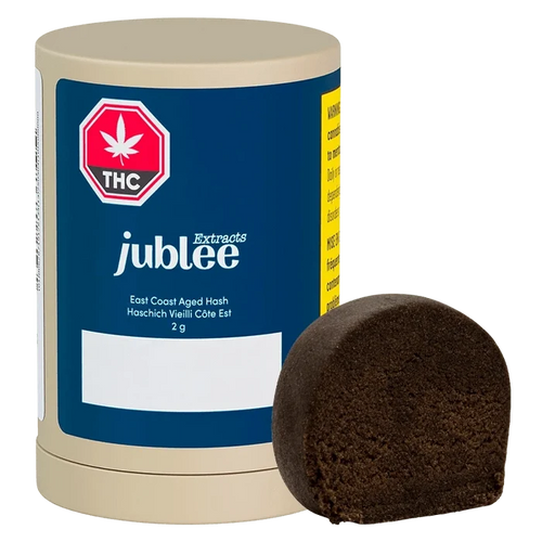 Front three-quarter view of a Jubilee Extracts East Coast Aged Hash 2 g cylinder with its dark brown half-disc of hash placed beside it.