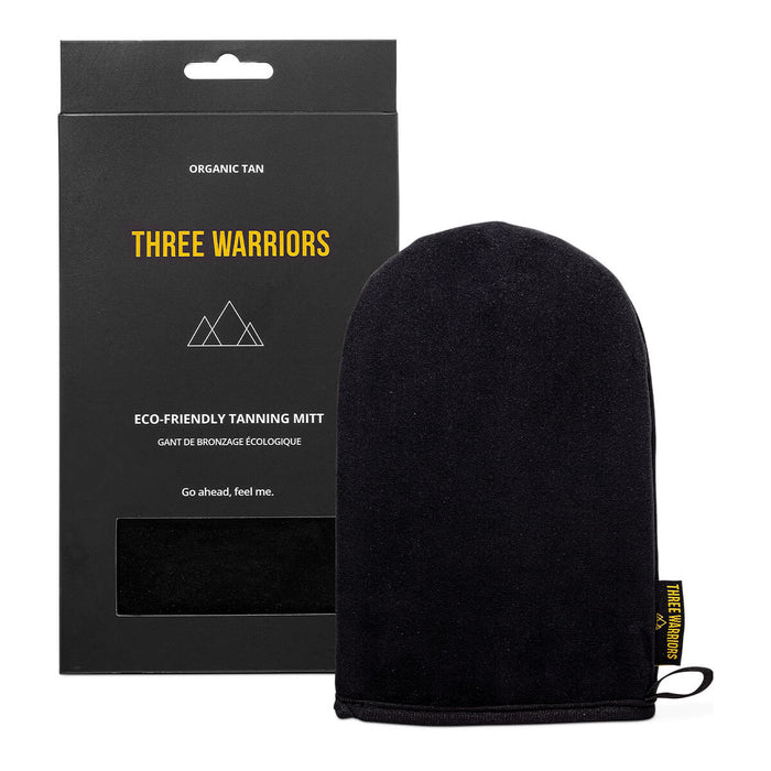 A black tanning mitt made out of a soft, velour material displayed next to its box.