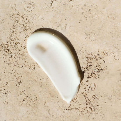 White cream smear on a beige textured background.