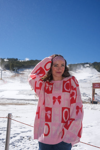 Person wearing a pink sweater with red patterns
