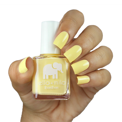 Hooray of Sunshine yellow nail polish on a medium skin tone, hand holding the bottle