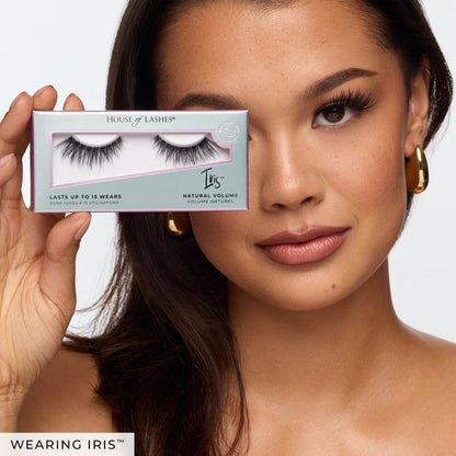 Close-up of a woman holding a House of Lashes Iris box beside her eye.