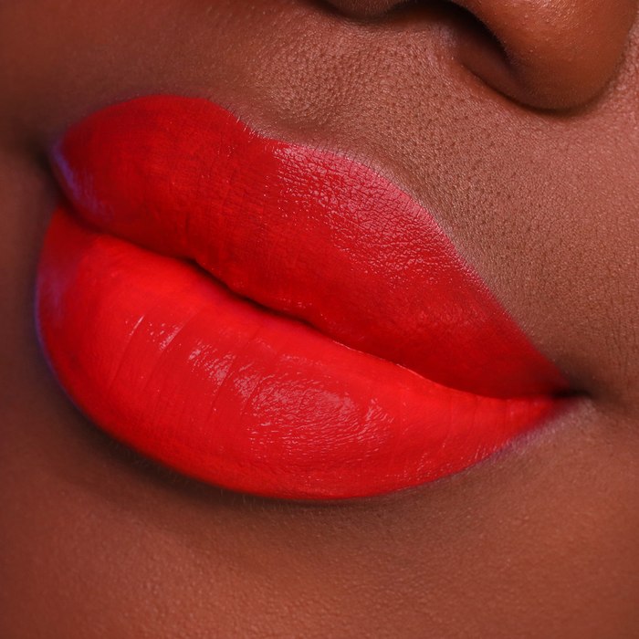 Island Girl orange red lipstick on lips, deep skin tone close-up