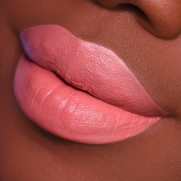 Just Enough peachy nude lipstick on lips, deep skin tone close-up