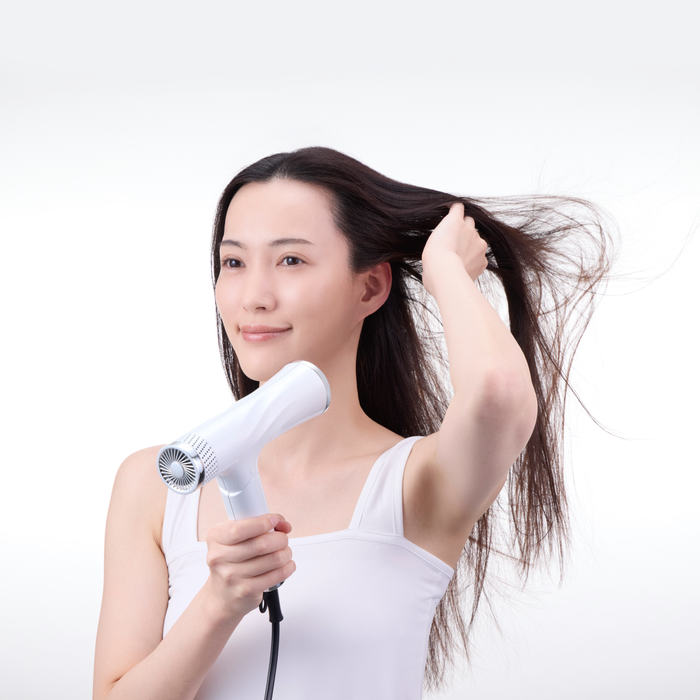 Woman using a hair dryer on a white background