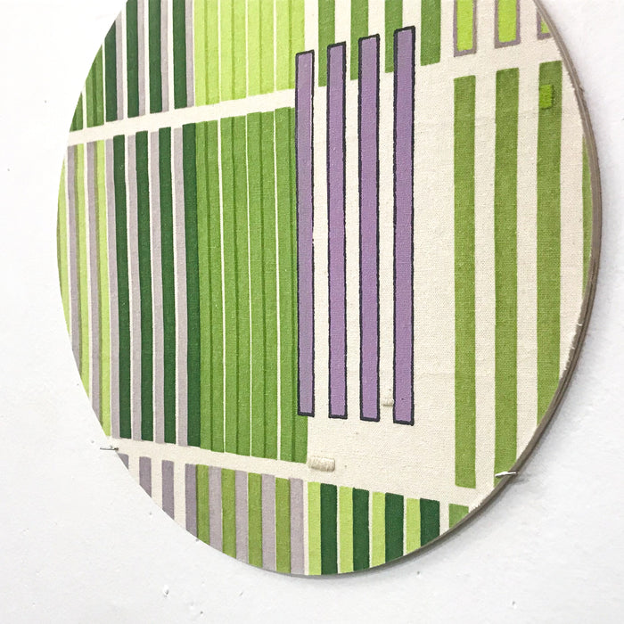 The artwork 'Line Study 1' by Molly Koehn features vertical stripes in varying shades of green and lavender on raw silk. The geometric composition alternates between thick and thin lines, creating a modern minimalist pattern on a circular birch mount. The embroidered texture adds depth to the precise linear arrangement.