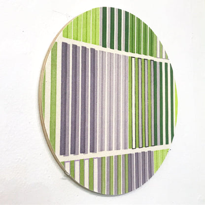 The artwork 'Line Study 2' by Molly Koehn features geometric vertical stripes in alternating shades of green and gray on raw silk, mounted on a circular birch panel. The composition creates a modern, minimalist pattern with clean parallel lines divided into distinct sections, showcasing a harmonious blend of natural and muted tones. By Molly Koehn.