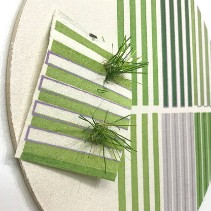 Line Study 4 by Molly Koehn features geometric stripes in green and white with contrasting purple accents, complemented by textural elements of artificial turf creating a three-dimensional effect. The mixed media artwork combines pigments on raw silk with astroturf patches, mounted on birch in a circular format, creating a modern minimalist composition.