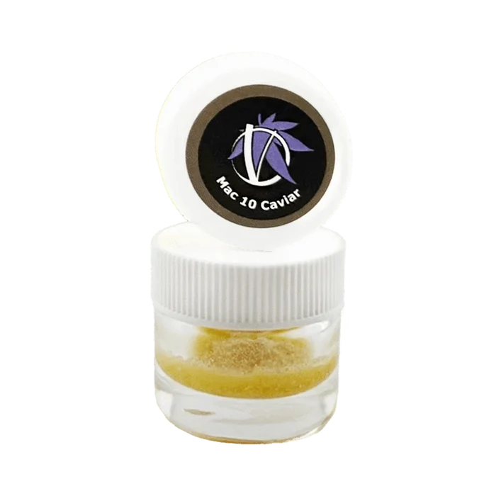 Close-up front view of a small clear jar with a white ribbed lid and opened cap showing a circular black logo reading "Mac 10 Caviar" above golden crumble inside, Mac 10 Caviar