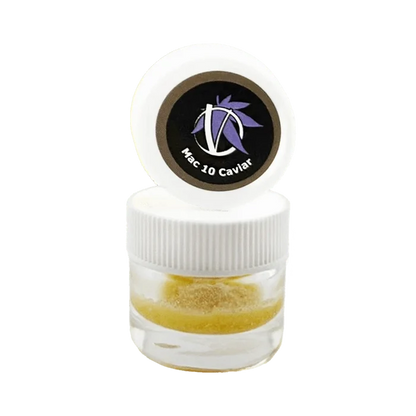 Close-up front view of a small clear jar with a white ribbed lid and opened cap showing a circular black logo reading "Mac 10 Caviar" above golden crumble inside, Mac 10 Caviar