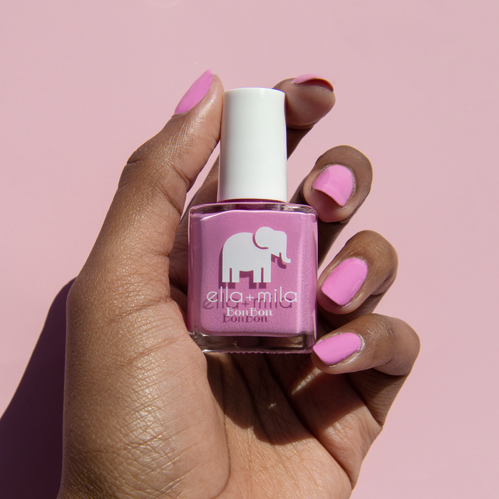 Macaruin My Diet pastel purple pink nail polish, hand holding the bottle on a pink background