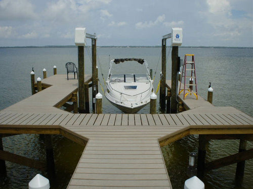 Boat docked at a wooden pier with a clear sky over calm waters in a marine setting