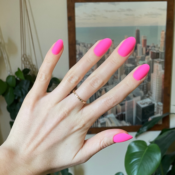 Matte Neon Flamingo - Press-On | Medium | Oval showing hand with medium oval neon pink matte press-on manicure indoors