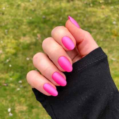 Matte Neon Flamingo - Press-On | Medium | Oval showing hand with medium oval matte neon pink press-on manicure outdoors