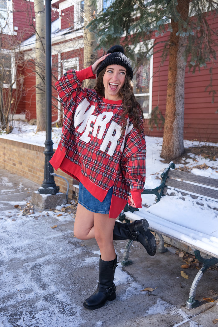 Person wearing a red plaid sweater with 'Merry' text