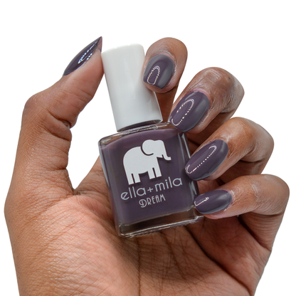 Night In dark purple nail polish on a deep skin tone, hand holding the bottle