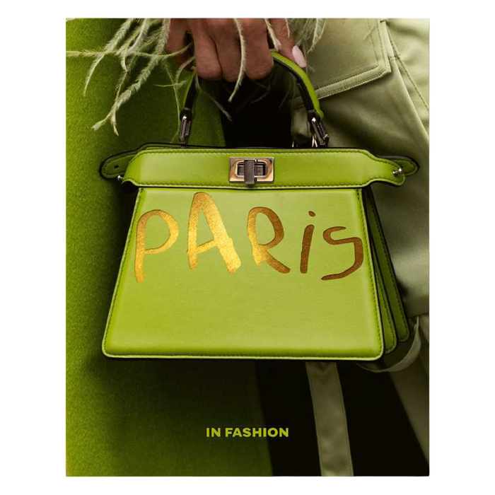 Green handbag with 'Paris' written on it, held by a person wearing a green coat.