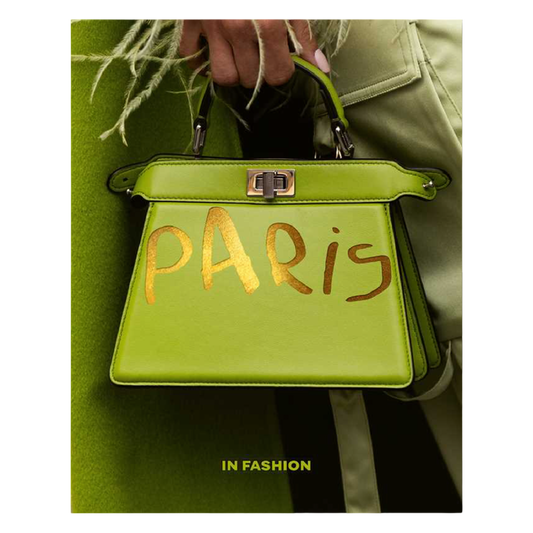 Green handbag with 'Paris' written on it, held by a person wearing a green coat.