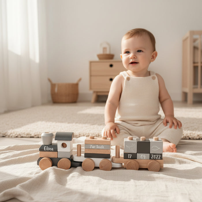 Baby im Kinderzimmer vor personalisiertem Holzzug zur Taufe mit Name und Taufdatum
