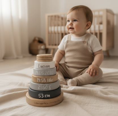 Baby spielt im Kinderzimmer mit personalisiertem Stapelturm aus Holz mit Geburtsdaten