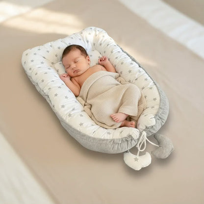 Baby im wendbaren tiSsi Babynest Grau/Weiß – Produktdarstellung mit gepolsterter Umrandung