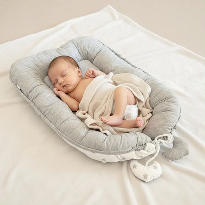 Baby im grauen tiSsi Babynest – Produktdarstellung des wendbaren Babynests