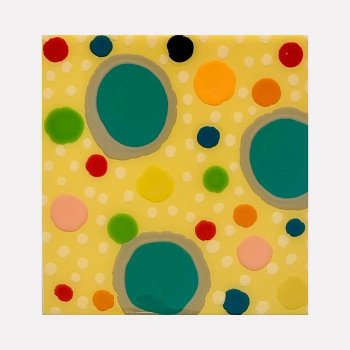 The artwork 'Piece of Cake 936' by Lori Kirkbride features playful circular patterns on a soft yellow background. Large turquoise circles anchor the composition, while smaller dots in red, orange, green, and pink create a dynamic, confetti-like scatter. The acrylic and resin artwork evokes a modern, whimsical aesthetic with its polka dot design.