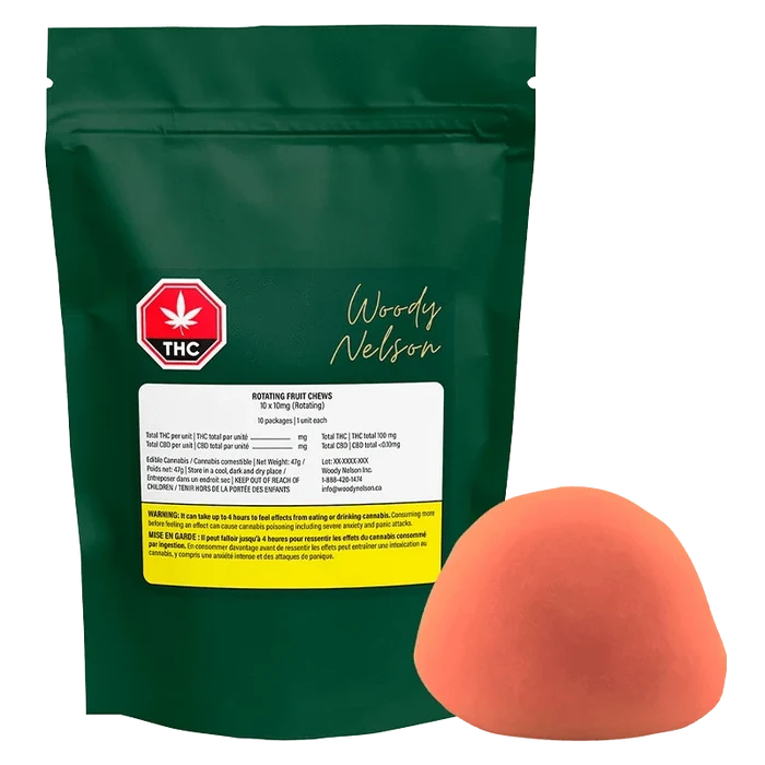 Front view of a green pouch labeled Woody Nelson Rotating Fruit Chews Gummies with a red THC symbol and a single orange half-sphere candy beside it