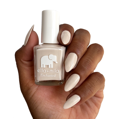 Secret Garden creamy nude nail polish on a deep skin tone, holding the bottle