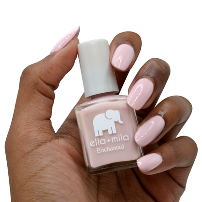 Spellbound pink lilac nail polish on a deep skin tone, holding the bottle