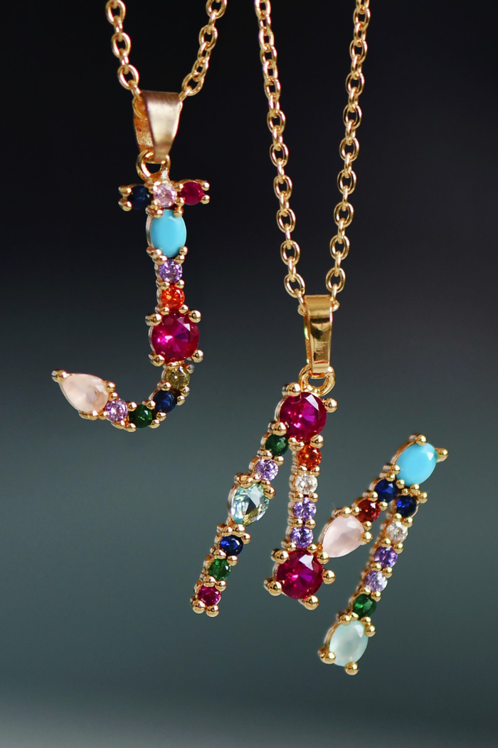 Gold necklace with colorful gemstone pendant on a dark background