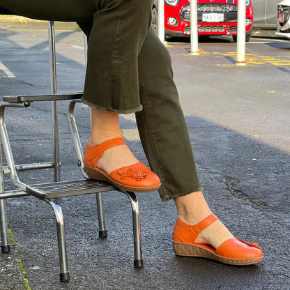 Smart orange sandal in soft leather uppers. Velcro strap, wedge sole unit with enclosed heel and enclosed toe. Comfortable women's sandal with floral detail. Women's shoes with cushioned footbed.