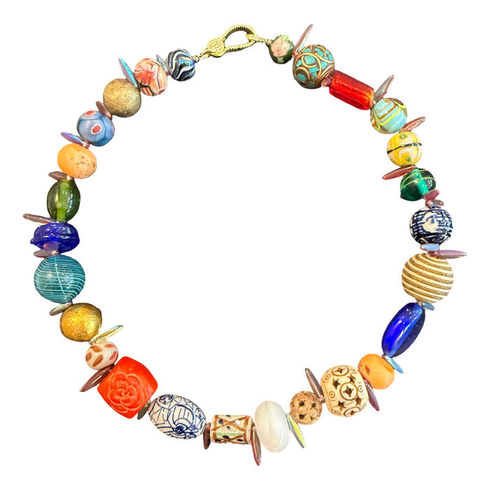 A handmade beaded necklace featuring a variety of colorful, patterned, and textured glass beads in blue, green, orange, yellow, and white, arranged in a circle on a plain white background.