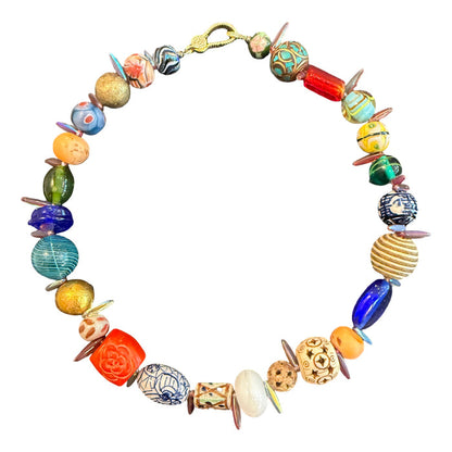 A handmade beaded necklace featuring a variety of colorful, patterned, and textured glass beads in blue, green, orange, yellow, and white, arranged in a circle on a plain white background.