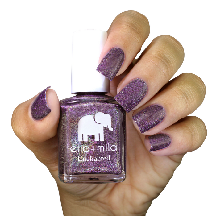 Violet Skies holographic deep violet nail polish on a medium skin tone, hand holding the bottle