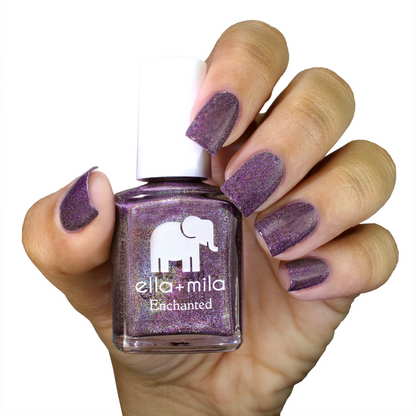 Violet Skies holographic deep violet nail polish on a medium skin tone, hand holding the bottle