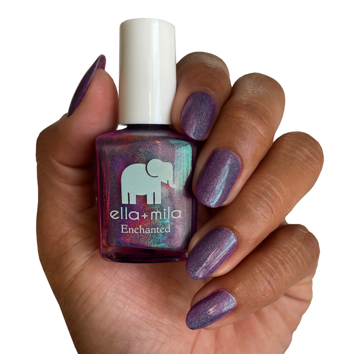 Violet Skies holographic violet nail polish on a deep skin tone, hand holding the bottle