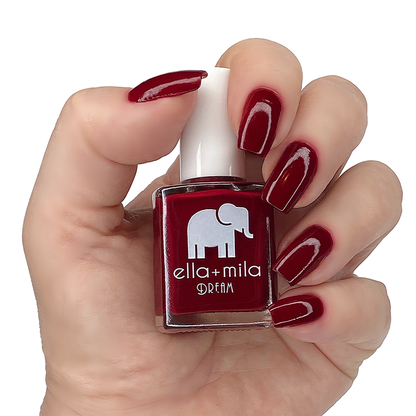 Wicked Red burgundy red nail polish manicure on a light skin tone with the bottle